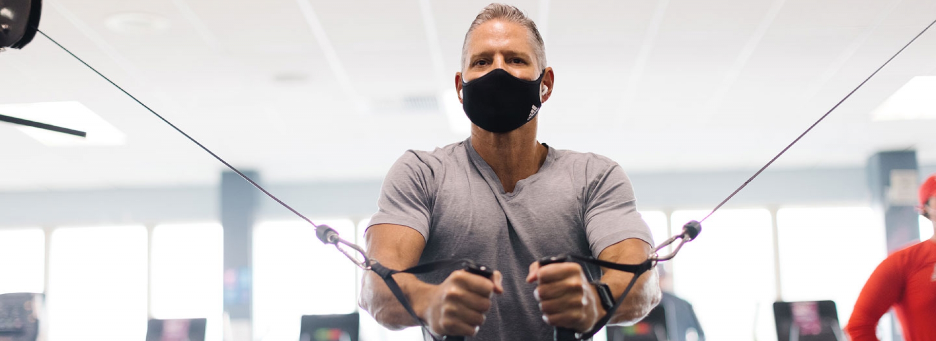 A man in a mask works on strength training at the YMCA.