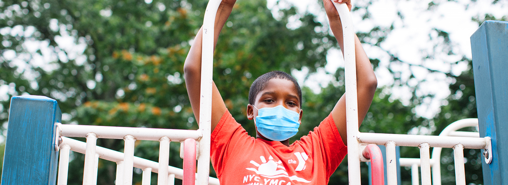 A boy in a mask playing outside at YMCA Camp