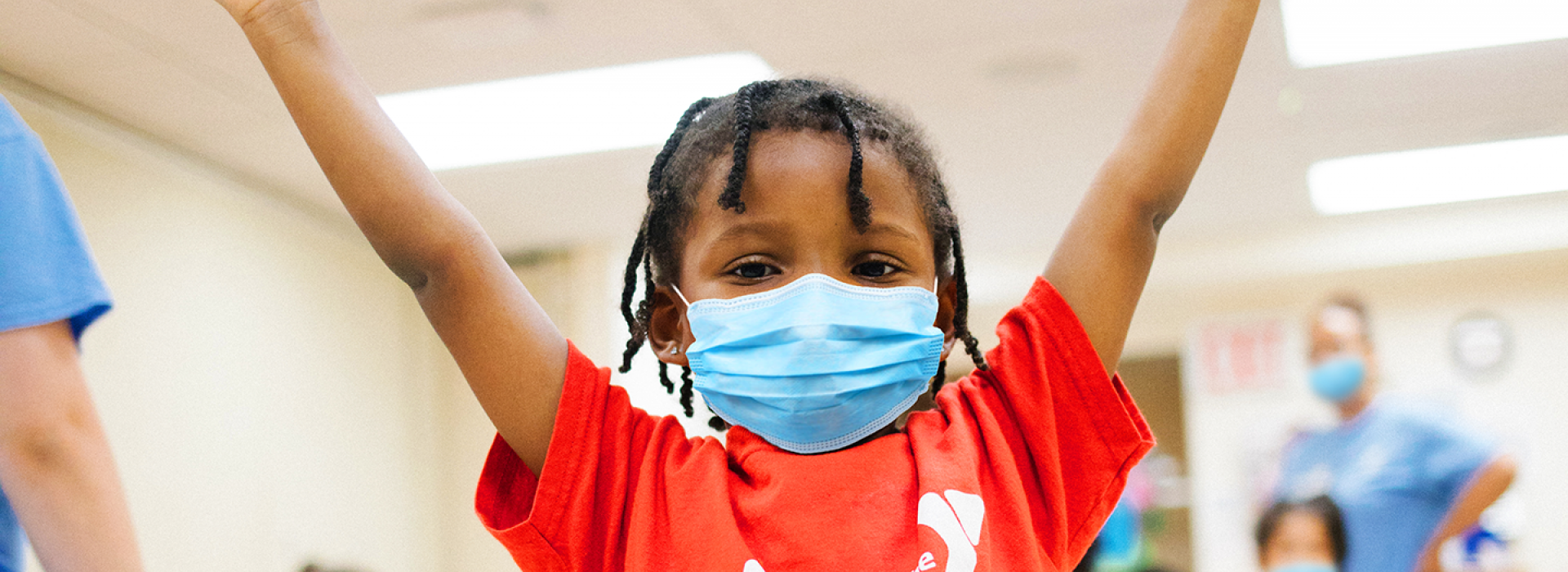 A girl in a mask posing with her arms up at Y camp