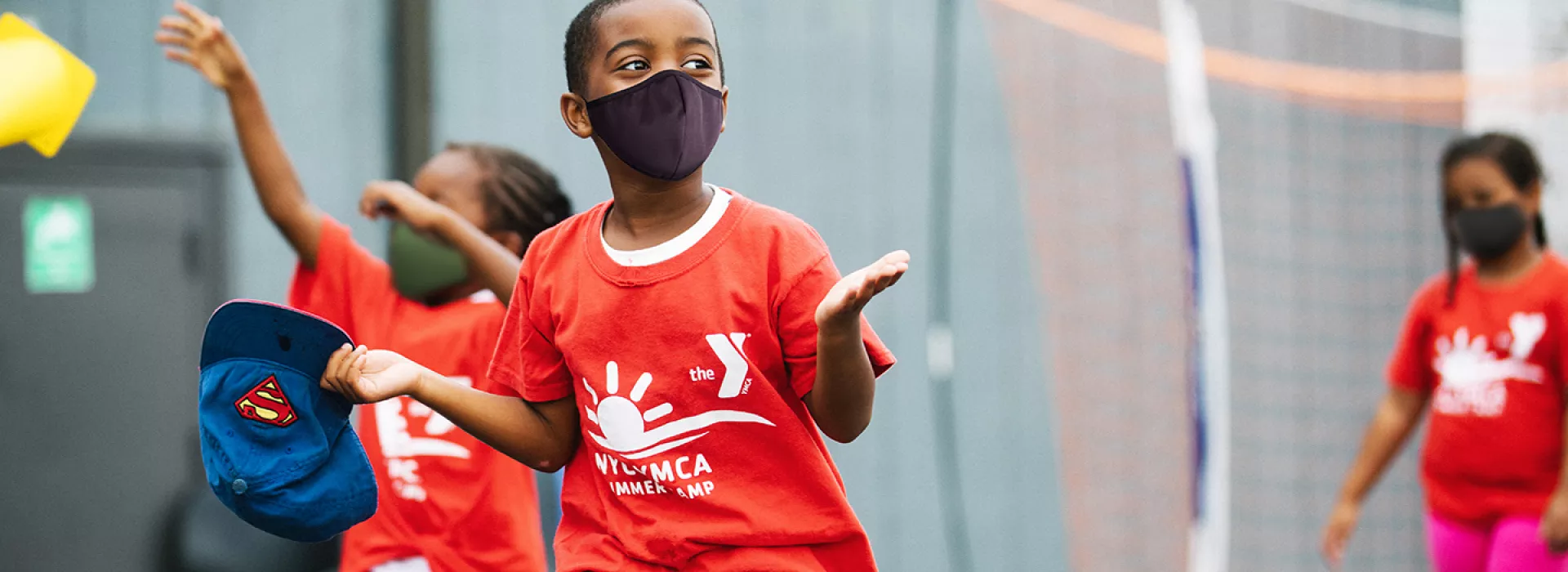 A boy in a mask running outside at YMCA Camp