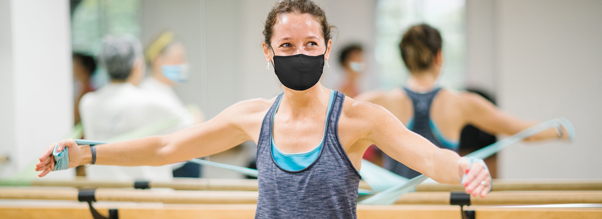 A woman wearing a mask participating in a group exercise class