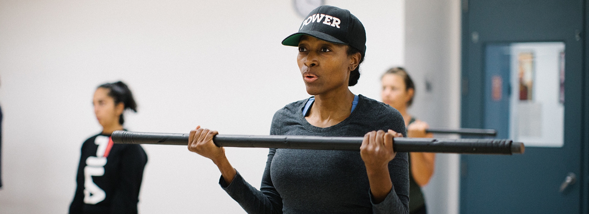 A woman lifting a bar in a group fitness class