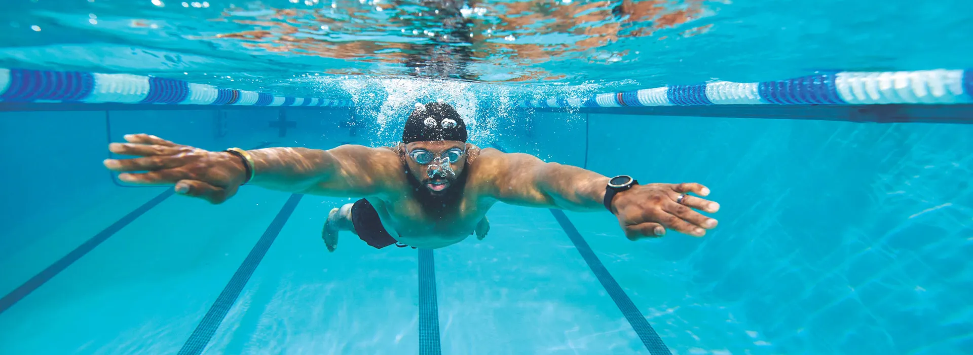 man swimming underwater in pool